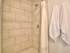 Close-up of tilework in bathroom shower with hooks for towels on wall at The Henry | Apartments in Tampa, FL.