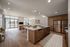 Modern open-concept apartment kitchen with sleek wood cabinetry, spacious island, and bright living area with expansive windows.