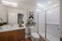 Modern bathroom with sleek wooden cabinetry, spacious shower, and elegant decor, featuring a large mirror and attractive wall art.