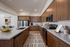 Modern kitchen with sleek wooden cabinetry, stainless steel appliances, and a spacious quartz island countertop, perfect for culinary enthusiasts.
