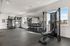 Modern fitness center with state-of-the-art equipment, including weight racks and exercise machines, in a bright and spacious setting.
