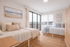 Bright bedroom with two beds, coastal decor, and large windows offering stunning views.
