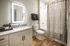 Modern bathroom with sleek vanity, illuminated mirror, and stylish shower curtain in a sophisticated apartment.