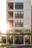 Modern apartment building exterior with stylish balconies and large windows reflecting the sunset glow.