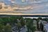 Breathtaking aerial view of a serene neighborhood with lush greenery, a picturesque lake, and a stunning sunset sky.