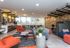 Modern communal lounge featuring chic orange and blue seating, stylish light fixtures, and a vibrant open space with ample natural light.