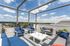 Luxurious rooftop terrace with stylish blue seating, offering breathtaking panoramic views of a serene lake under a clear sky.