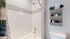 Modern bathroom design featuring elegant white tiles and a convenient woven wall organizer.