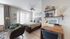 Elegant bedroom with stylish decor, featuring a cozy wooden bed, modern desk, and decorative shelving. Natural light fills the space through large windows with vertical blinds.
