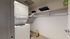 Charming laundry room with stacked washer and dryer, ample shelving, and stylish decor.