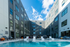 Modern apartment courtyard with a sparkling pool, chic lounge chairs, and vibrant seating options against a backdrop of stylish building architecture.
