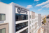 Modern urban apartment building featuring sleek architecture and expansive windows, set against a vibrant cityscape.