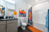Chic bathroom featuring modern fixtures, vibrant artwork, and stylish storage shelves.
