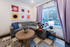 Chic and cozy apartment living room with modern gray sectional sofa, colorful abstract art displays, and vibrant decor, offering a welcoming natural light ambiance.