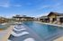 Luxurious outdoor pool area with stylish loungers, shaded cabanas, and pristine blue water set against a picturesque residential backdrop.
