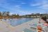 Inviting outdoor pool area with sleek poolside loungers, modern umbrellas, and a serene gated community backdrop.