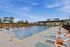 Inviting outdoor swimming pool area with modern loungers and umbrellas, perfect for relaxation under a clear blue sky.