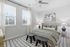 Bright and cozy bedroom featuring a stylish bed with patterned bedding, modern art, and natural light streaming through large windows.