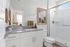 Bright and modern bathroom featuring sleek granite countertop, white cabinetry, and glass-enclosed shower with stylish decor.