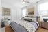 Inviting bedroom with a plush bed adorned with elegant botanical patterns, cozy armchair, modern art pieces, and warm ambient lighting.