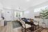 Bright living room with elegant modern decor, featuring a cozy sectional sofa, stylish round dining table with chairs, large windows, and an inviting indoor plant.