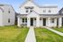 Charming modern duplex with a pristine white exterior, inviting front porch, and well-manicured lawn offering stylish suburban living.
