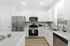 Contemporary kitchen with sleek stainless steel appliances, white cabinetry, and elegant granite countertops. Natural light from large windows enhances the modern design.