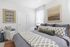 Elegant and cozy bedroom with modern decor, featuring a plush bed adorned with patterned linens, soft natural lighting, and stylish framed artwork.
