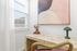 Chic home office nook with a sleek marble desk, elegant abstract art, and a stylish green lamp near a bright window.