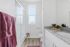 Modern bathroom featuring sleek granite countertops, elegant glass shower, and stylish maroon accents.