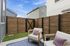 Charming private patio with cozy seating, vibrant cushions, and a wooden privacy fence under a clear blue sky.
