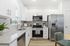 Modern kitchen with sleek stainless steel appliances, white cabinetry, and granite countertops. Bright and inviting space with natural light and stylish decor.