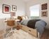 Charming bedroom with cozy bed, stylish desk, and large window showcasing a scenic view, perfect for relaxation and productivity.