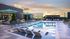 Luxurious rooftop pool area with stylish loungers, large outdoor screen, and stunning sunset views.