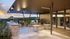 Chic rooftop patio with modern seating, barbecue grills, and stunning sunset views over lush hills.