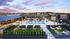Luxurious rooftop oasis featuring a sparkling pool, chic lounge areas, and breathtaking city views under a vibrant sunset.