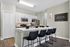 Modern kitchen featuring sleek white cabinetry, a stainless steel fridge, stylish backsplash, and a cozy breakfast bar with black seating.