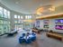 Luxurious community lounge with modern chandeliers, large windows, and entertainment screens, featuring a pool table and comfortable seating.