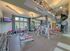 Modern fitness center featuring state-of-the-art exercise equipment, bright natural lighting, and a stylish spiral staircase.