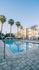 Luxurious apartment complex with a sparkling outdoor pool and elegant palm trees, perfect for relaxation and leisure.