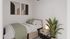 Cozy bedroom with modern artwork, elegant plant, and soft lighting creating a serene atmosphere.