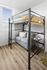 Modern apartment room with a loft bed over a cozy gray sofa, complemented by stylish wooden flooring and natural light from large windows.