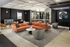 Modern apartment lobby with stylish orange sectional sofa, elegant gray chairs, and large windows for natural light.