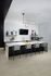 Modern kitchen area with sleek white countertops, chic bar stools, and stylish decor elements, creating a welcoming and sophisticated atmosphere.