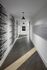 Modern apartment hallway with elegant pendant lighting, artistic wall design, and sleek wooden flooring.