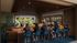 Vibrant communal lounge with people enjoying a sports game on a large screen, highlighting a lively social atmosphere with comfortable seating and modern design.