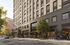 Contemporary urban apartment building with stylish facade, abundant windows, and vibrant street life.