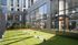 Modern urban living space featuring a vibrant outdoor yoga area with lush green grass and large glass windows revealing a stylish interior gym.
