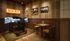 Chic gaming nook with dual screens, racing simulator, vintage car art, and cozy seating in a warm-toned ambiance.
