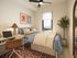Cozy bedroom with stylish decor, featuring a comfortable bed, sleek desk with laptop, and a large window offering scenic views.